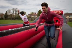 Two guys running down the inflatable bungee run to see which one can get the furthest.