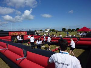 A referee standing next to the Human Table Football while a groups of school children play the football game