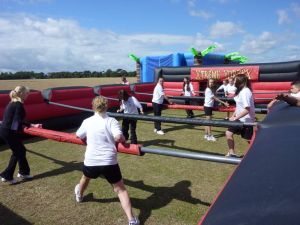 Group of school children playing football inside the inflatable human table football game at a school activity day.