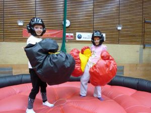 Two girls with giant boxing gloves standing on the inflatable bouncy boxing game.