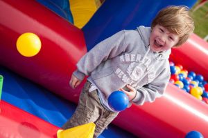 A close up of a very happy boy, smiling whilst playing on the Inflatable Children's Playzone