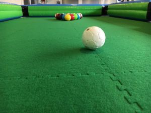 Close up of giant football pool balls inside an inflatable surround and on an astroturf pitch.