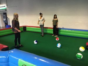 Females with giant pool balls made out of footballs to create an inflatable game of football pool.