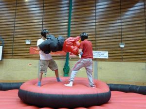 Two men standing on the rocking podium of the inflatable Bouncy Boxing game.