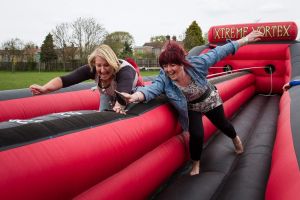 Two ladies smiling and laughing as the play on the inflatable bungee run game.