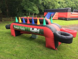 Keepy Uppy is a red and black inflatable game which is set up for a corporate event at an outdoor location.