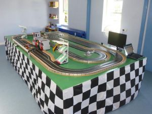 A large Scalextric racing circuit complete with buildings, track, slot cars and computerised leaderboard.