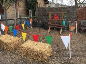 Traditional side stall game of tin can alley set up with brightly coloured bunting.