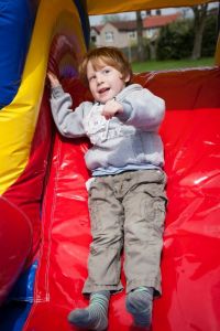 A small boy sliding down an inflatable slide on the Children's play zone